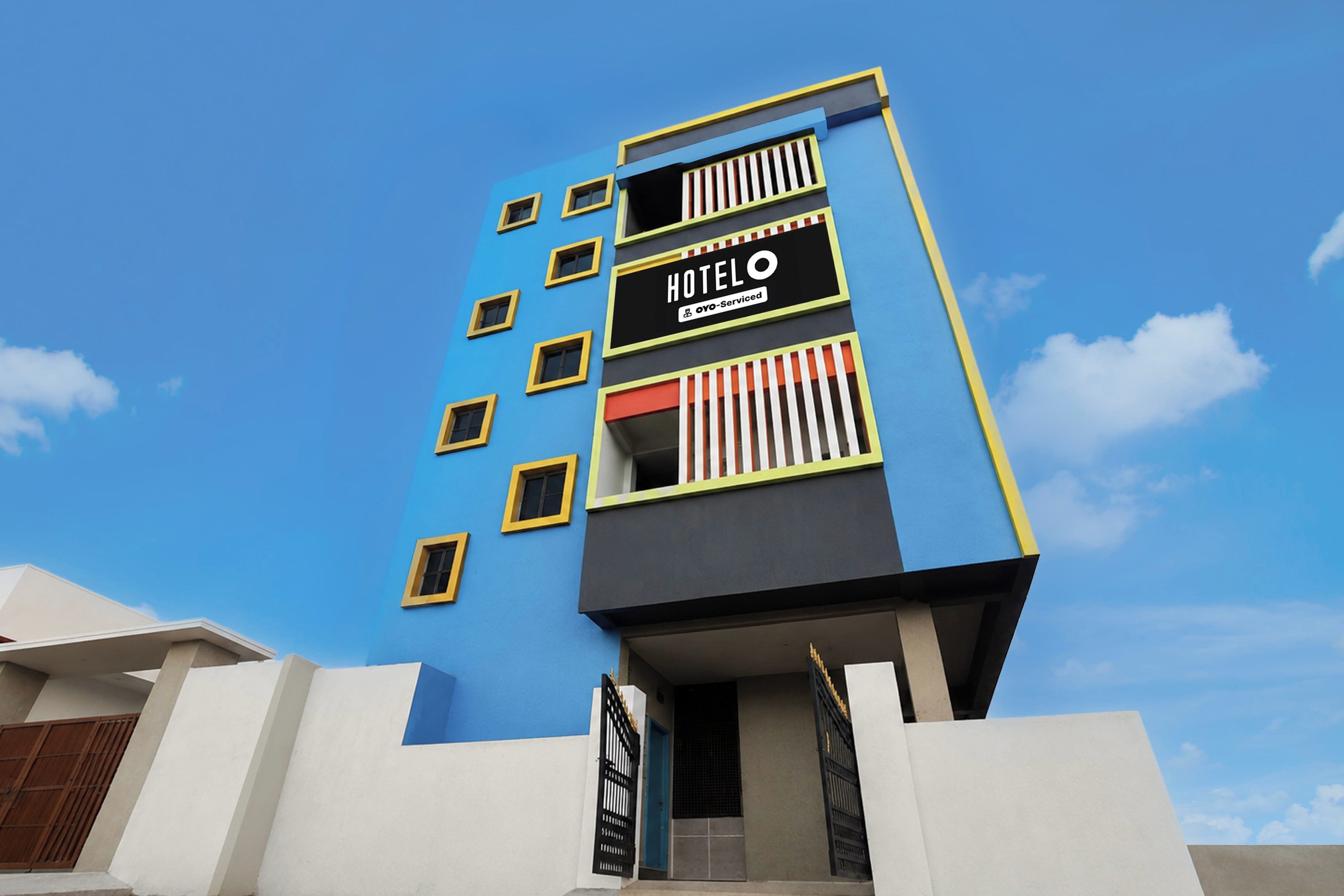 A multi-story hotel building with a blue facade and a sign indicating it is serviced by OYO.