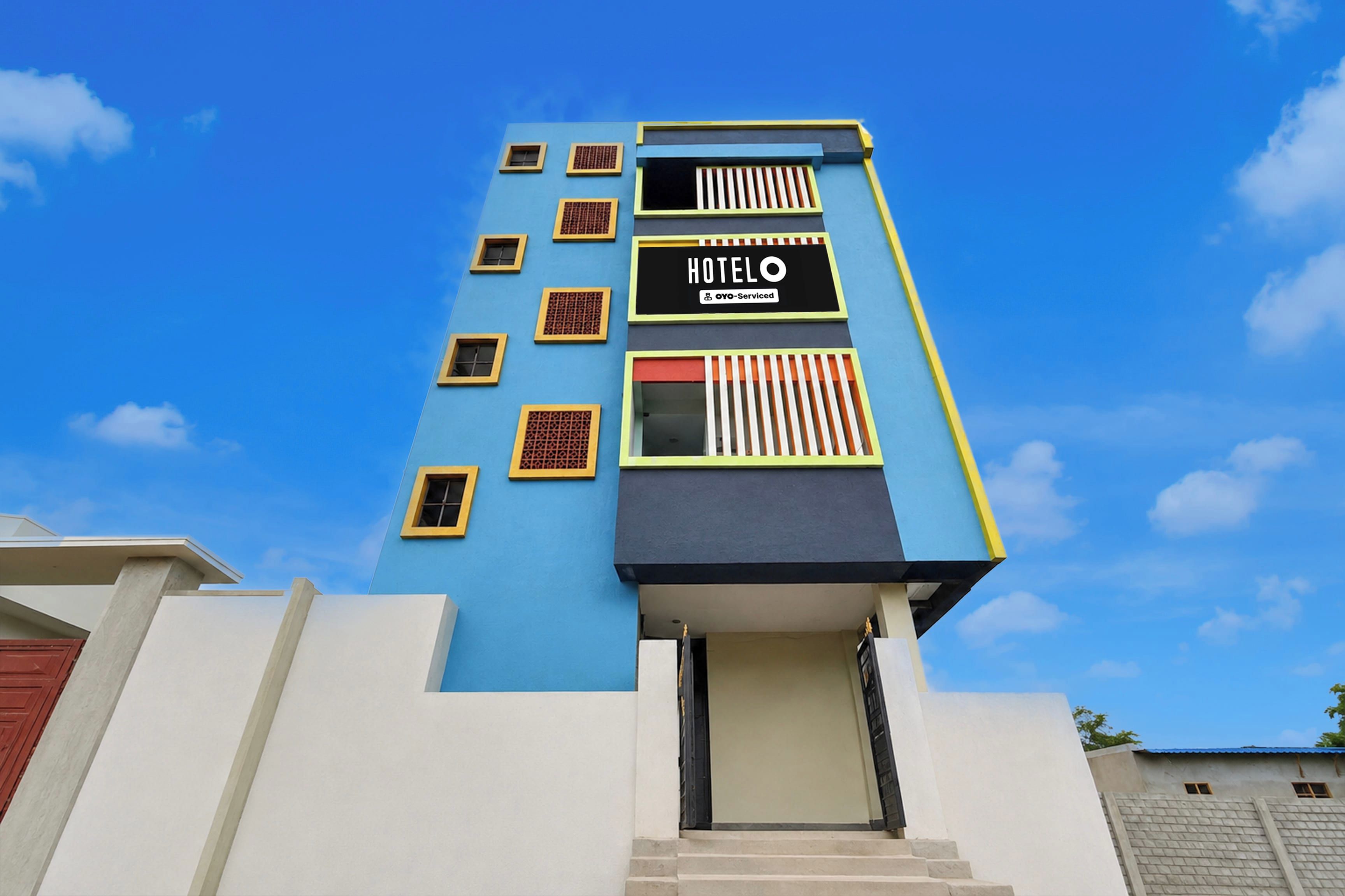 Un edificio de hotel con fachada azul, numerosas ventanas y un letrero que indica que cuenta con servicios de OYO.