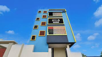 Un edificio de hotel con fachada azul, numerosas ventanas y un letrero que indica que cuenta con servicios de OYO.