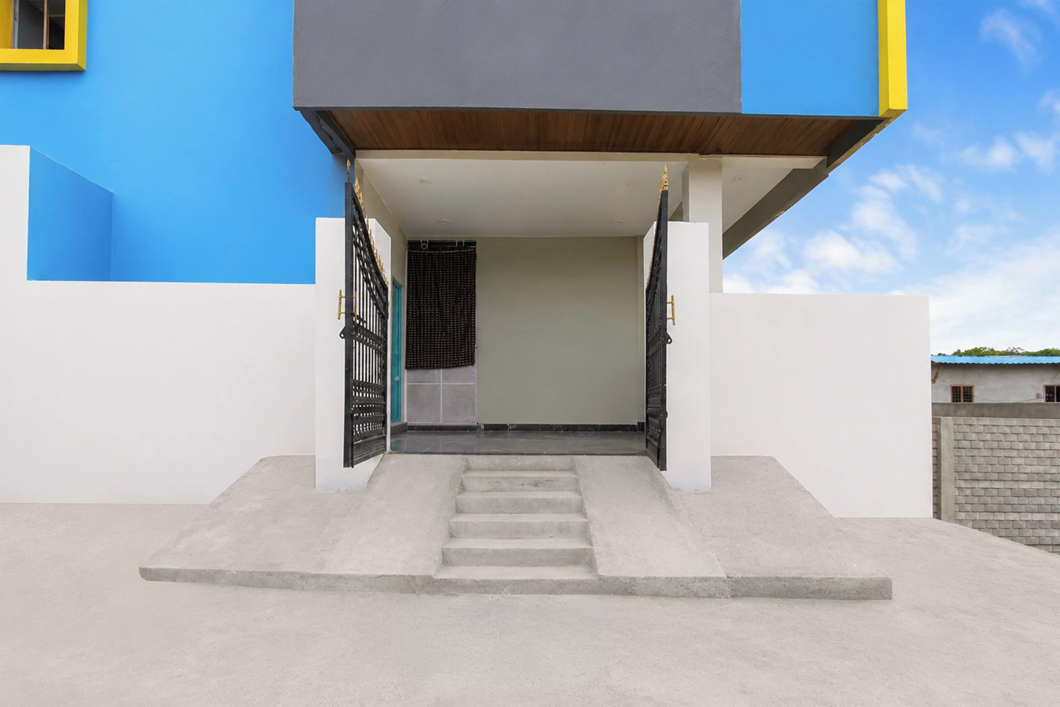 A modern building entrance with a concrete staircase leading up to a door with a black metal gate.