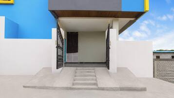 A modern building entrance with a concrete staircase leading up to a door with a black metal gate.