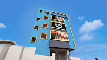 Un hotel de varios pisos con fachada azul, un letrero que indica que es administrado por OYO y una escalera que conduce a la entrada.