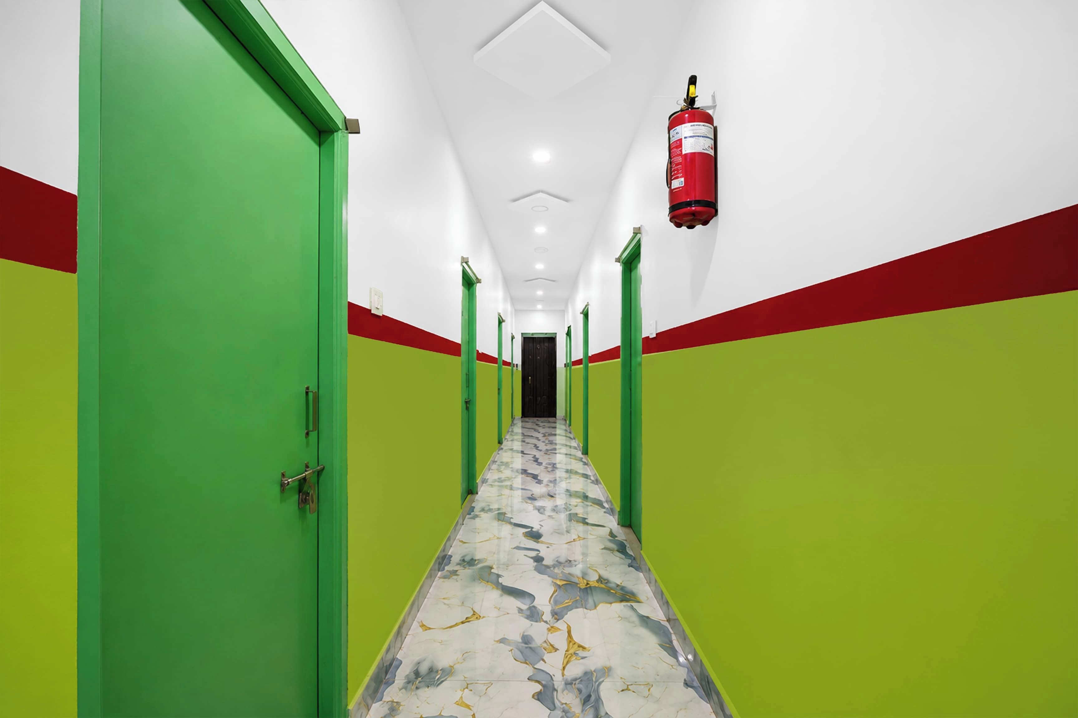 A hallway with green and red walls, a marble floor, and a fire extinguisher mounted on the wall.