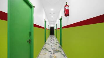 A hallway with green and red walls, a marble floor, and a fire extinguisher mounted on the wall.