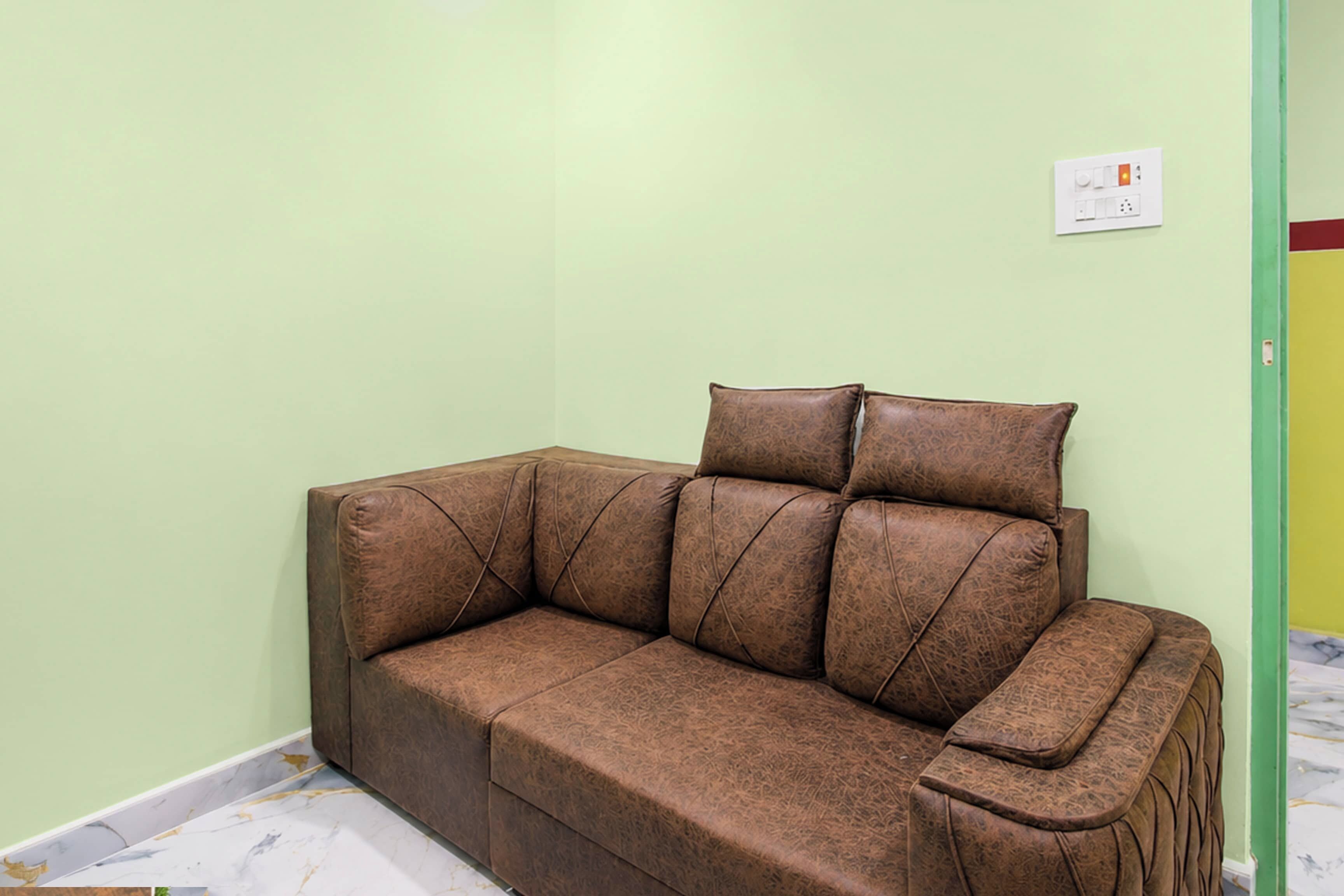 A brown leather sofa with a matching ottoman in a room with light green walls and a marble floor.