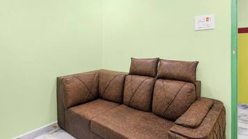 A brown leather sofa with a matching ottoman in a room with light green walls and a marble floor.