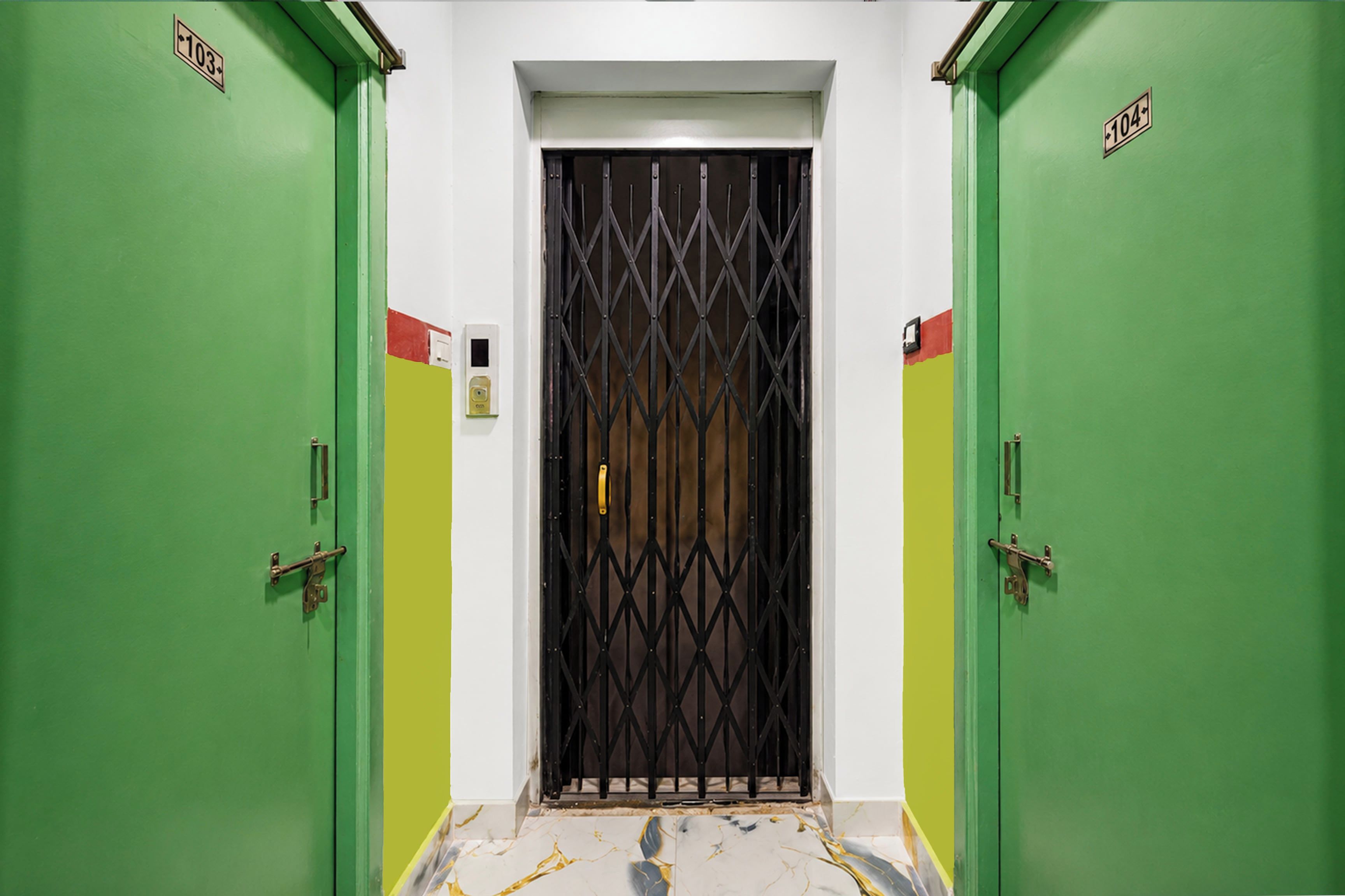 Un pasillo con puertas verdes numeradas 103 y 104, que conduce a una habitación con una puerta con barrotes.