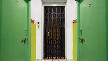 Un pasillo con puertas verdes numeradas 103 y 104, que conduce a una habitación con una puerta con barrotes.