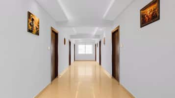Un pasillo largo y estrecho con paredes de tonos claros y suelo brillante, que conduce a una habitación luminosa con un ventanal grande.