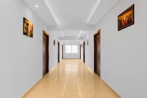 Passadís llarg i estret amb parets de tons clars i un sòl brillant, que condueix a una habitació ampla i lluminosa amb un gran finestral.