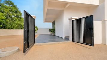 A modern building with two black gates, a paved courtyard, and potted plants.