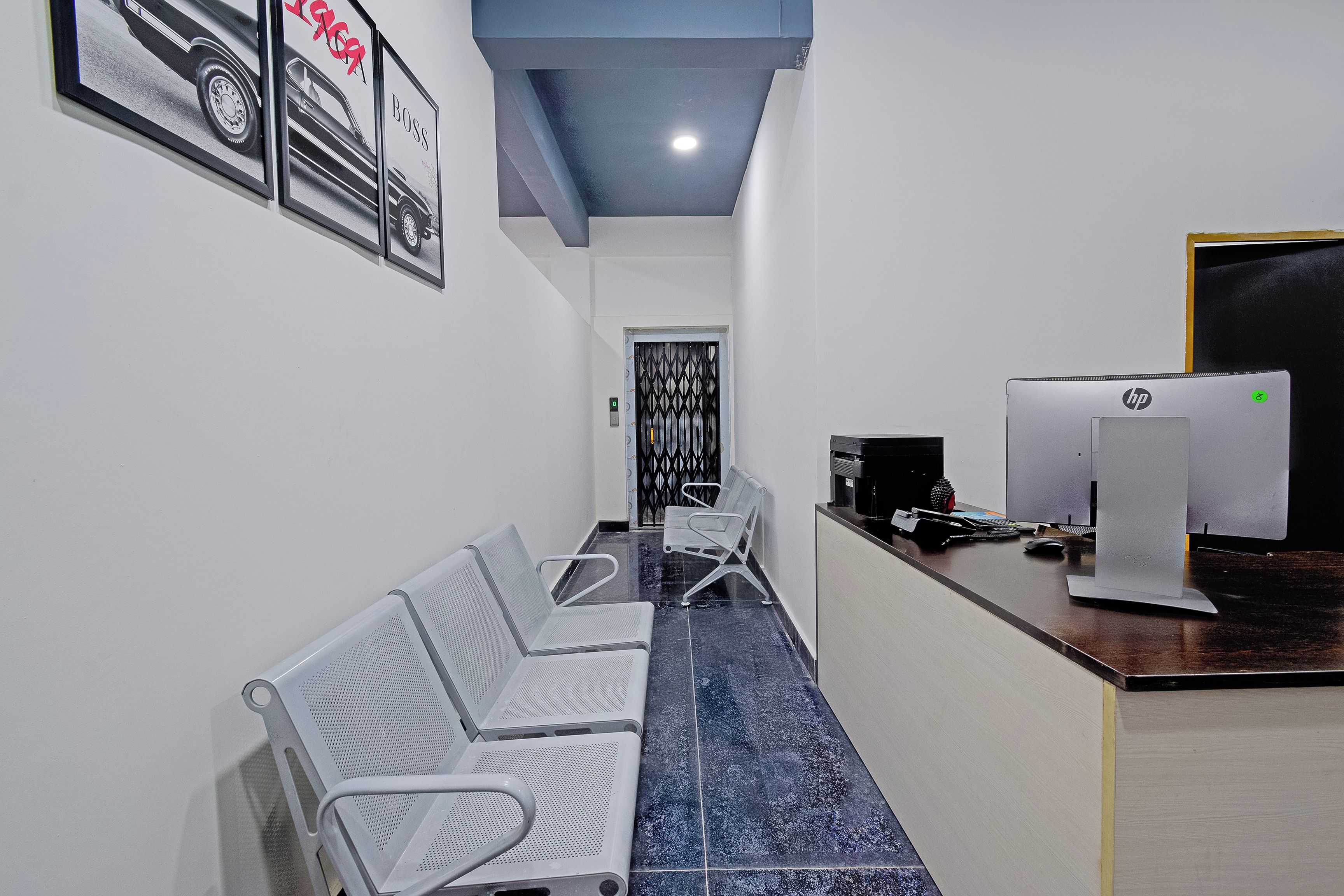 A conference room with a long table, several chairs, a reception desk with HP computers, and framed pictures on the wall.