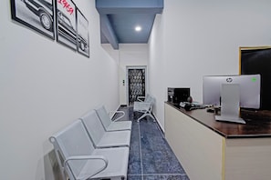 Un salón de conferencias con una mesa larga, varias sillas, un mostrador de recepción con computadoras HP y cuadros en la pared.