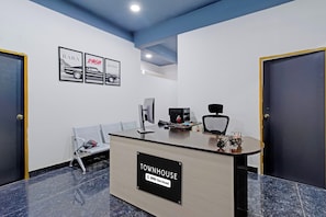 A reception desk with a sign reading 'TOWNHOUSE OYO-Serviced,' a computer, a phone, and a chair. - Townhouse MJR Square Mall Formerly Seton (Hyderabad)