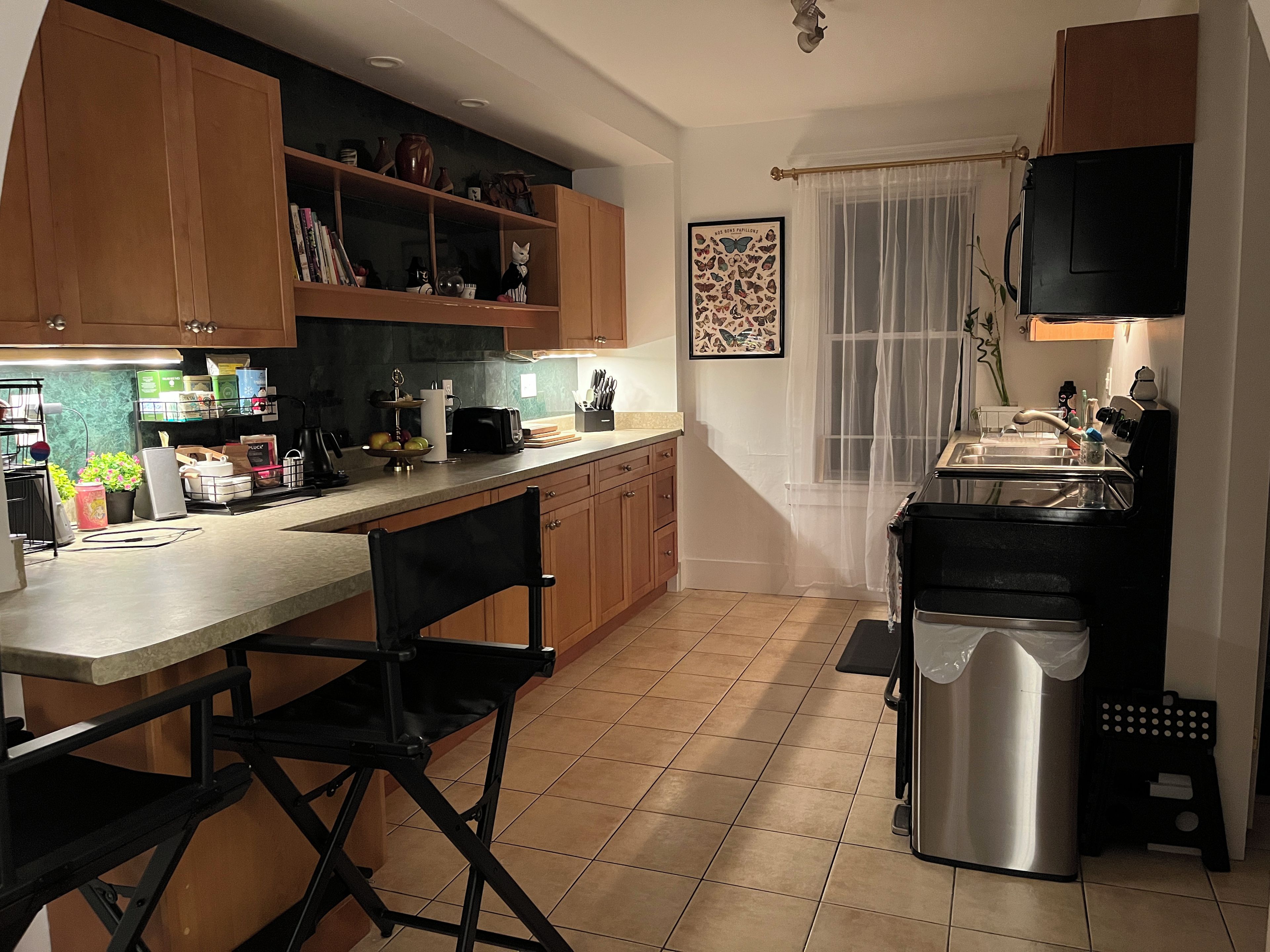 Une cuisine avec des armoires en bois, un plan de travail, un évier et une poubelle.