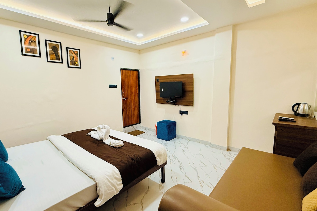 Una habitación de hotel con una cama, un escritorio, un televisor y un ventilador de techo.