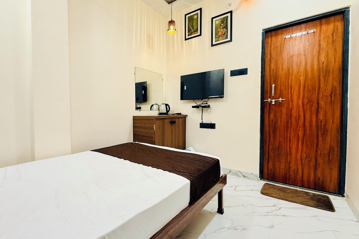 Un dormitorio con cama, un armario de madera, un televisor y una puerta.