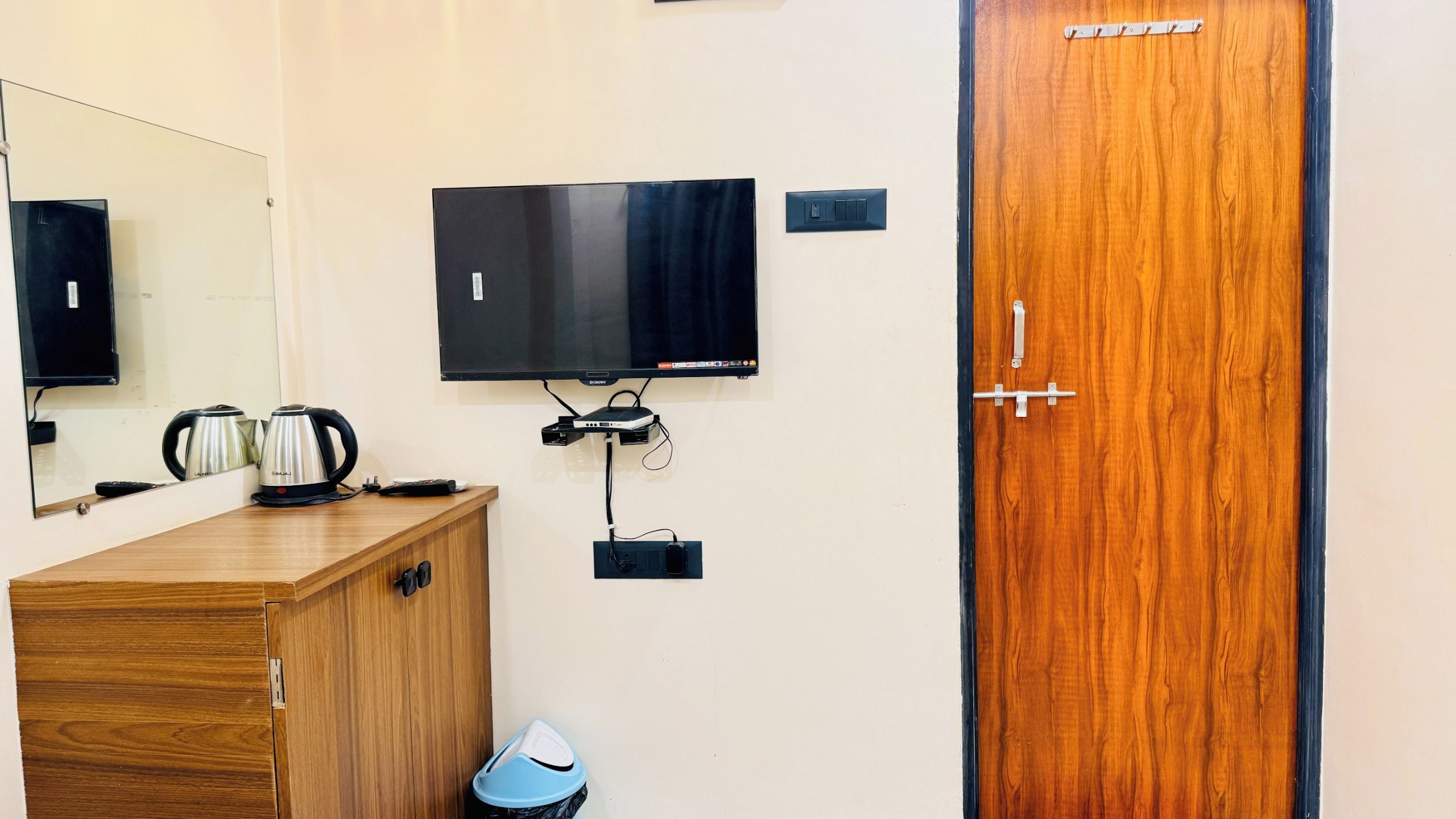 Una camera d'albergo con un armadietto in legno, una televisione a parete e una porta con maniglia.