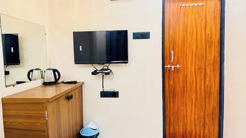 Habitación de hotel con un armario de madera, un televisor montado en la pared y una puerta con manija.