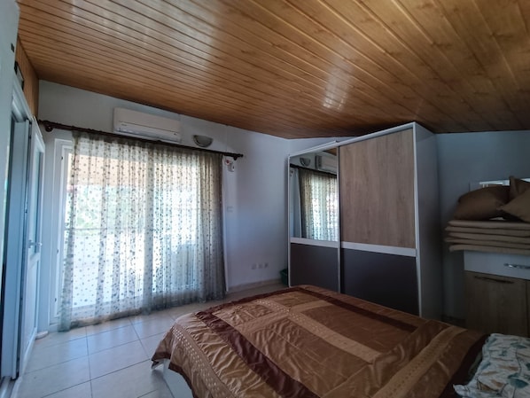 Un dormitorio con cama, armario y ventana con cortinas.
