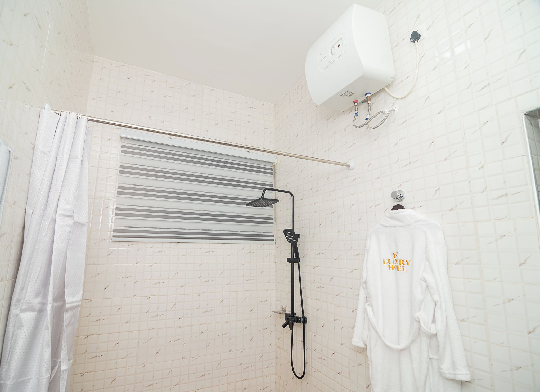 A bathroom with a shower, a towel rack with a robe, and a towel rack with a towel.