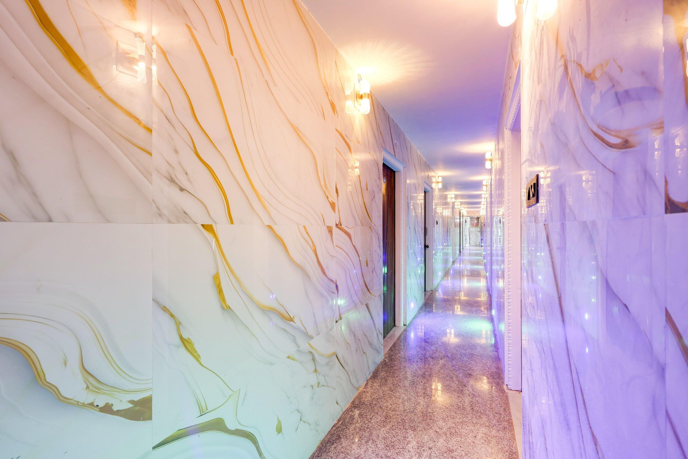 A marble-lined hallway with doors and light fixtures.