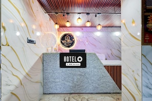 Un comptoir d’accueil avec un mur en marbre et une enseigne indiquant que l’établissement est géré par OYO.