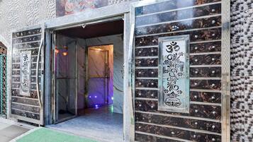 A building entrance with a glass door, a green mat, and decorative panels with inscriptions.