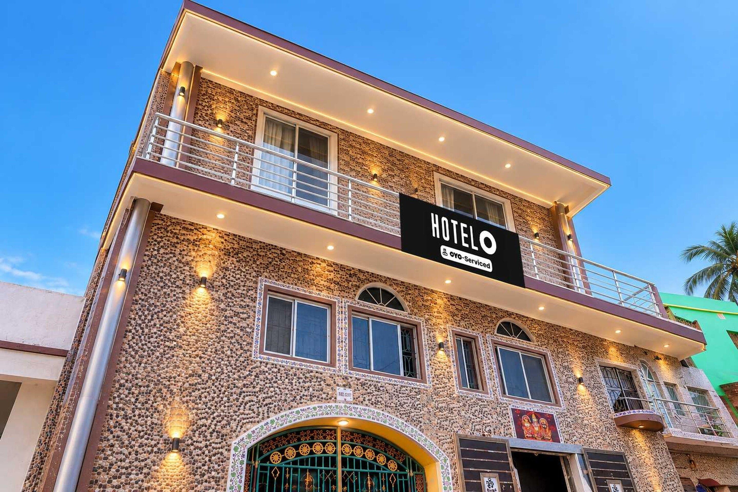 Ein mehrstöckiges Hotel mit steinverkleideter Fassade, Balkonen und einem Schild, das anzeigt, dass es von OYO geführt wird.