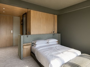 Un dormitorio moderno con cama, armario de madera y un banco empotrado.