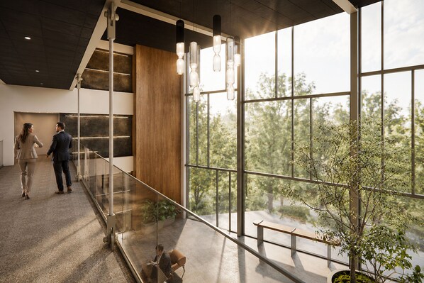 A modern interior with a glass railing, large windows, and a view of trees.