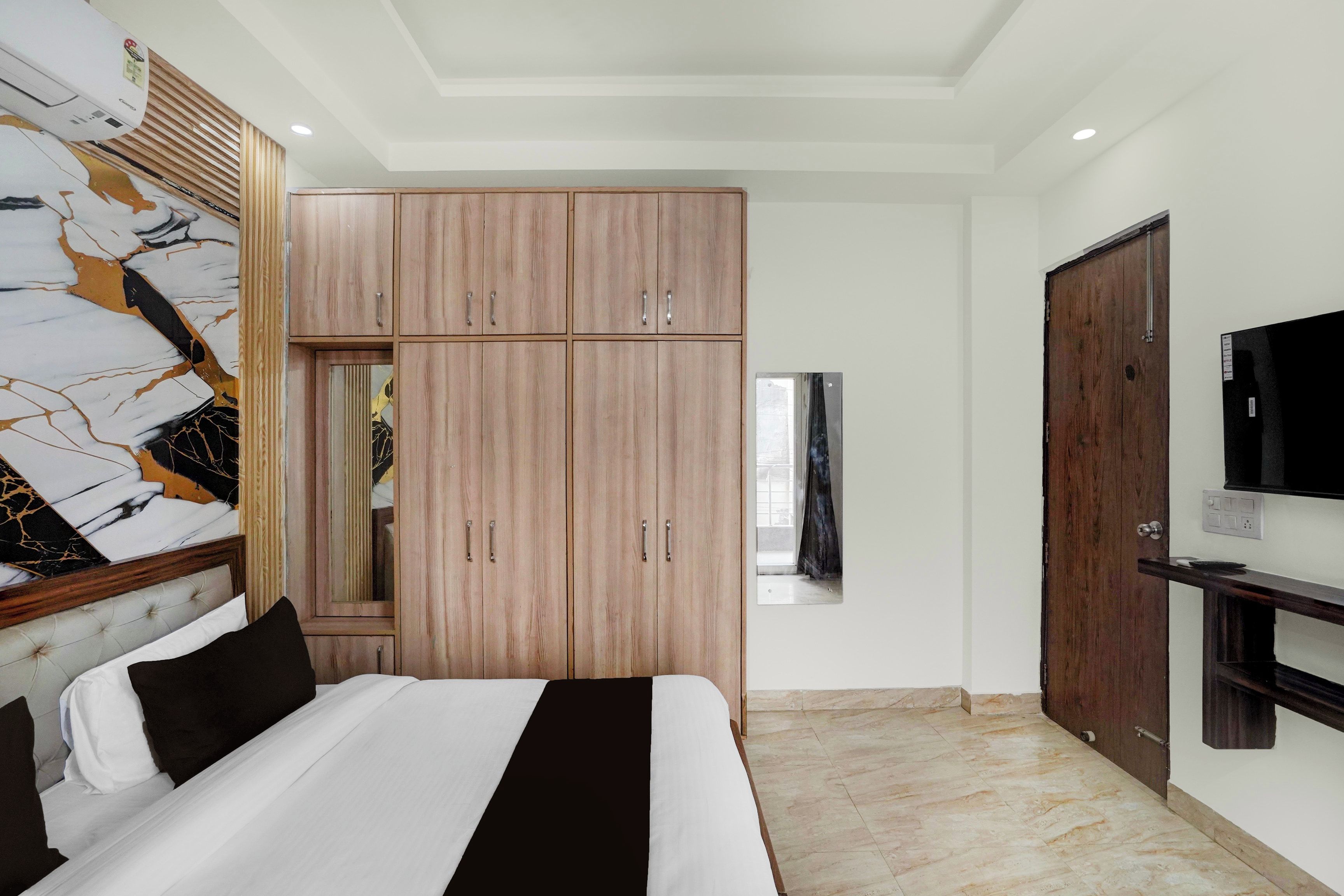 Un dormitorio con cama, armario, televisión y espejo.