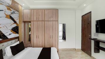 Un dormitorio con cama, armario, televisión y espejo.