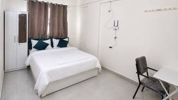 A bedroom with a bed, a chair, a desk, and a wardrobe.