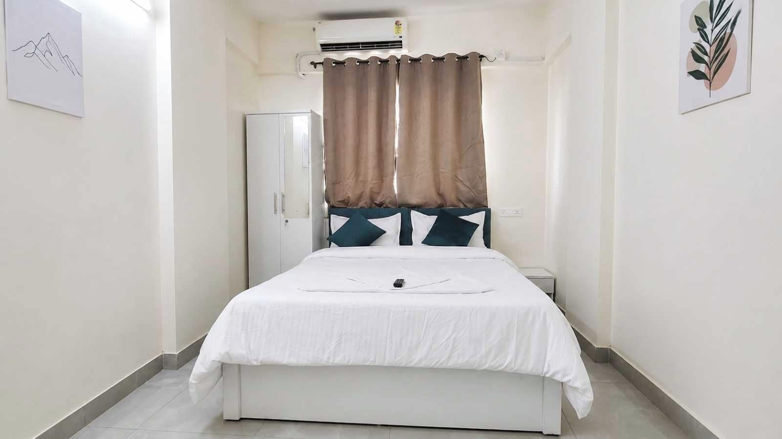 Een slaapkamer met een bed, gordijnen, een kledingkast en een wandairconditioner.