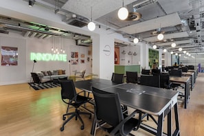 Ufficio con un lungo tavolo, sedie e un cartello al neon con la scritta 'INNOVATE'.