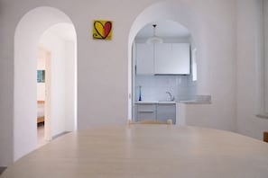 A modern kitchen with white cabinets, a light wood dining table, and a colorful heart-shaped artwork on the wall. - Alvillino, Ischia - Sea View Villa with Private Pool (Forio)