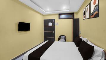 A hotel room with a bed, a television mounted on the wall, a door, and a window.