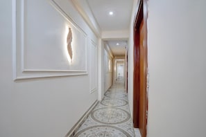 Um corredor com piso estampado, um detalhe decorativo na parede e uma porta de madeira.