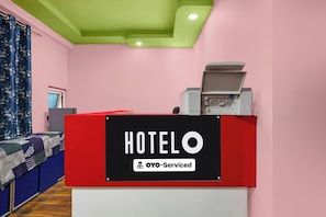 A hotel reception desk with a sign indicating it is OYO-Serviced.
