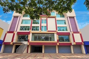 A multi-story building with a central entrance, large windows, and a staircase leading to the ground floor. - Hotel Rudransh Residency (Adityapur)
