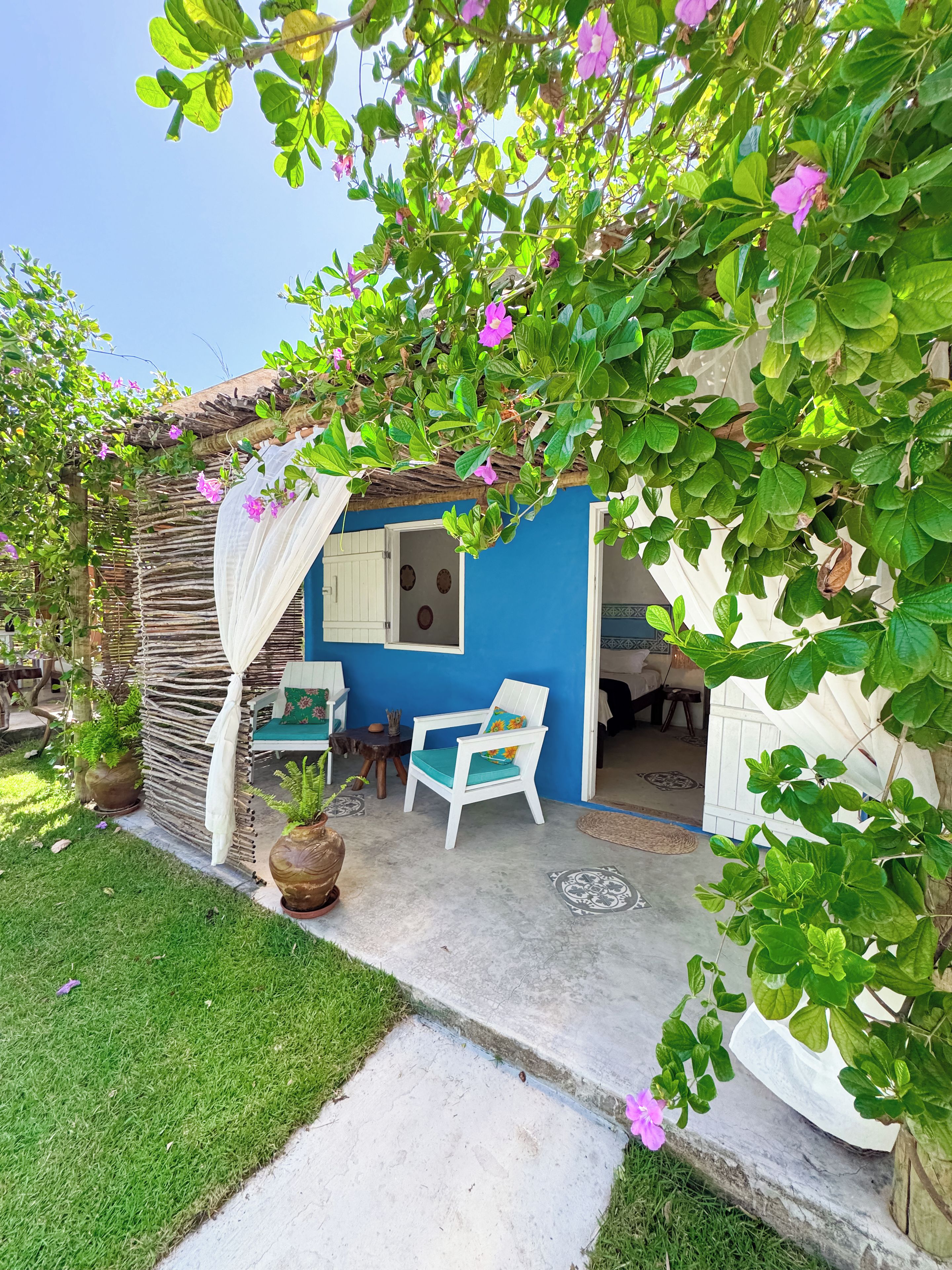 Uma casa azul com uma cadeira branca e uma mesa na varanda.