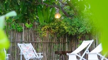 Piscina com espreguiçadeiras e cerca de bambu.