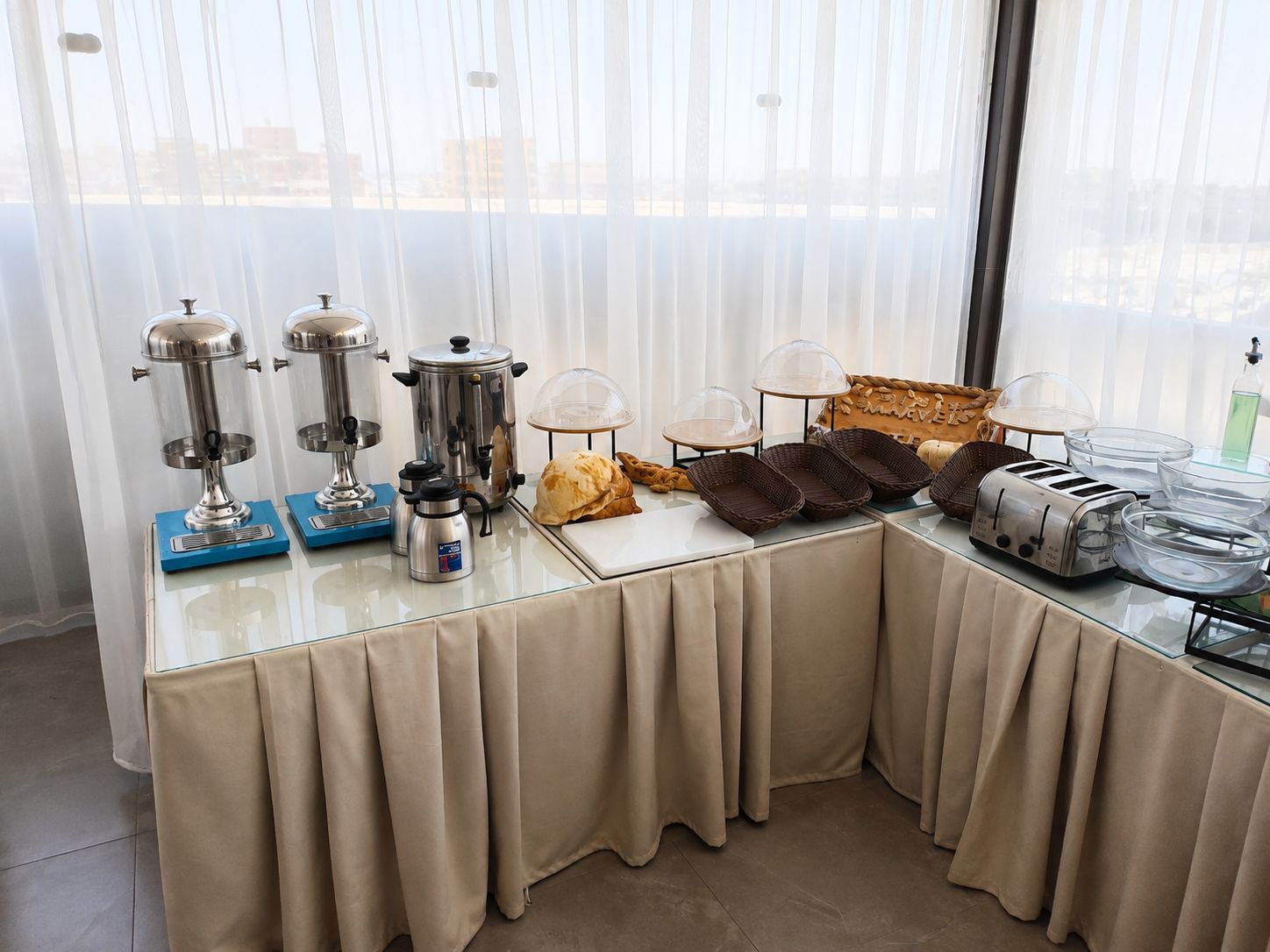 A breakfast buffet setup with coffee makers, a bread basket, and toasters.