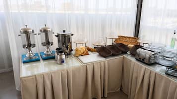 A breakfast buffet setup with coffee makers, a bread basket, and toasters.