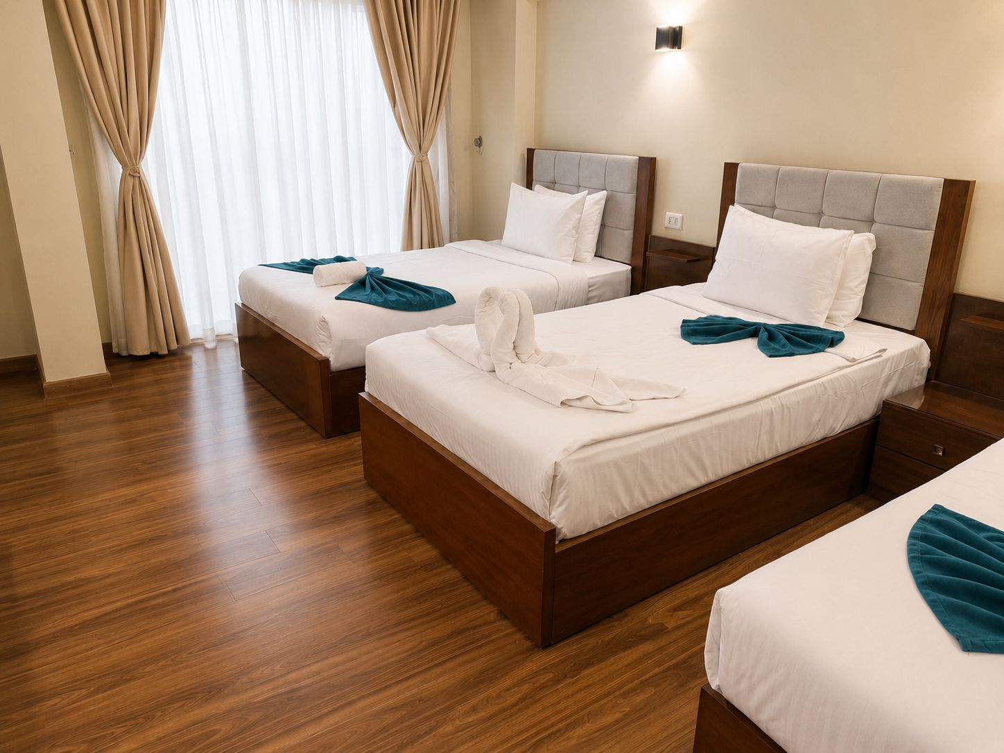 Habitación de hotel con dos camas, piso de madera y una ventana con cortinas.