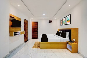 Un dormitorio moderno con cama, mesita de noche y televisor montado.