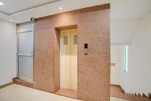 Un ascensor amb un panell de control, una porta i una paret amb un relleu decoratiu.