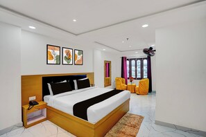 A modern hotel room with a large bed, bedside table, and a small table with a vase of flowers.