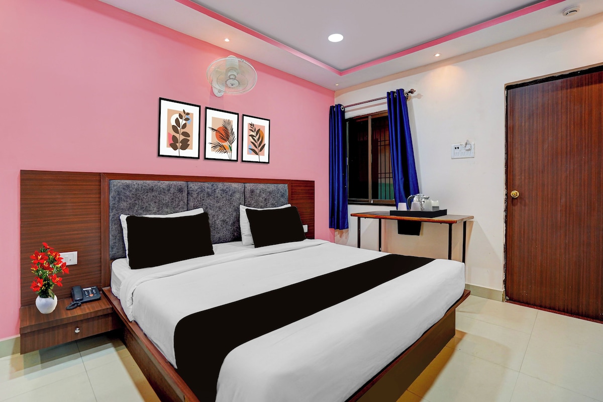 Habitación de hotel con cama, mesita de noche, decoración en la pared, ventilador de techo y puerta.